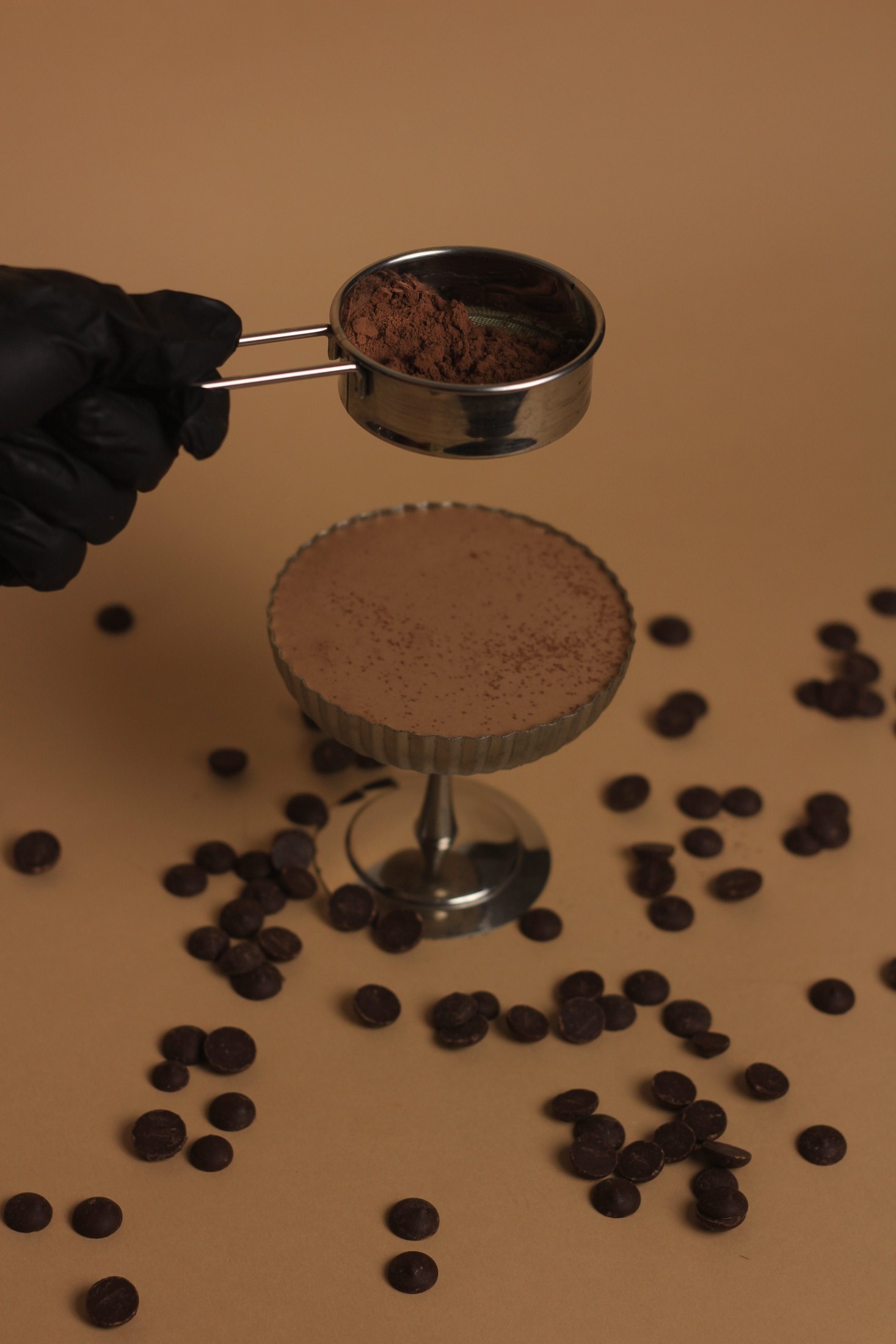 Cocoa being sifted over a dessert in a coupe glass