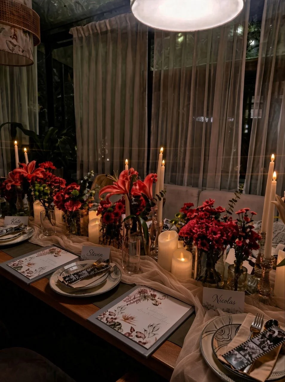 A candlelit dinner table with flowers and individual place settings